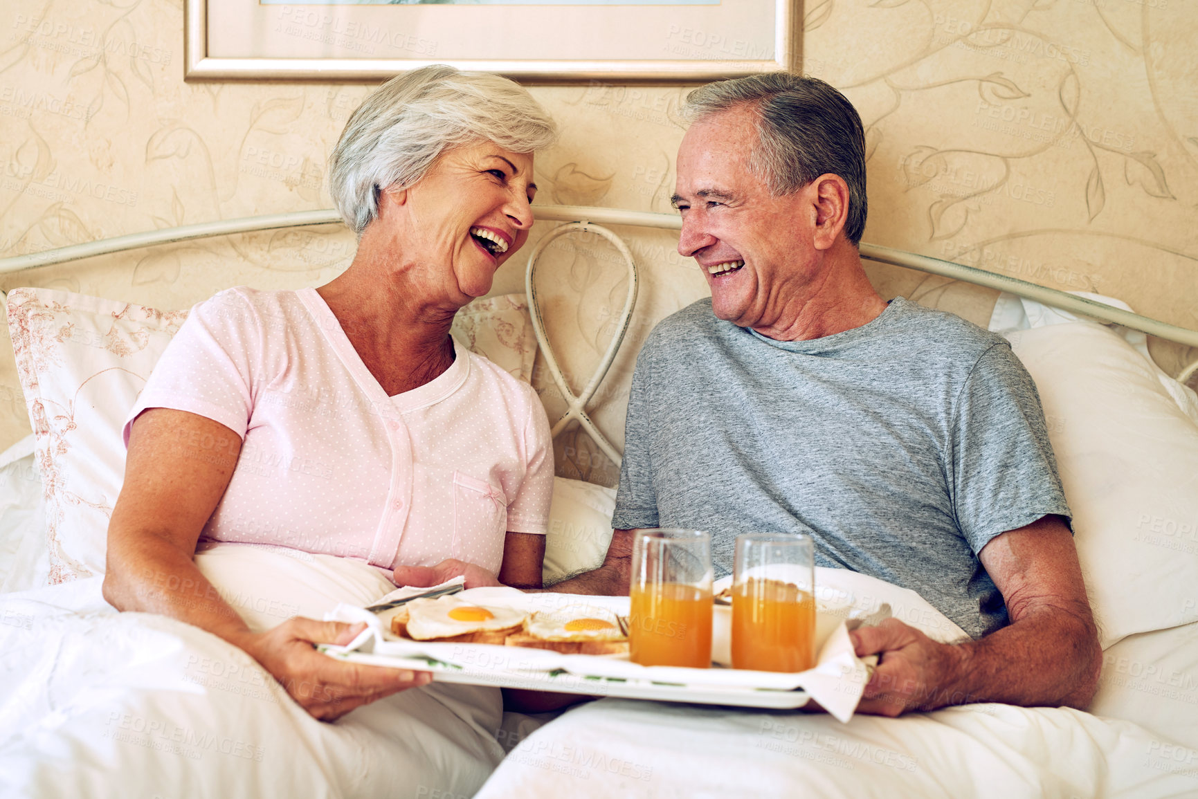 Buy stock photo Cropped shot of a senior couple having breakfast in bed together