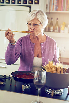 Buy stock photo Shot of a senior woman cooking in her kitchen