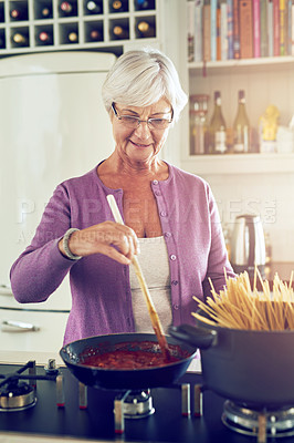 Buy stock photo Shot of a senior woman cooking in her kitchen