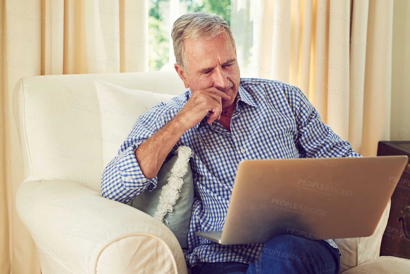 Buy stock photo Shot of an elderly man using a laptop in his lounge at home