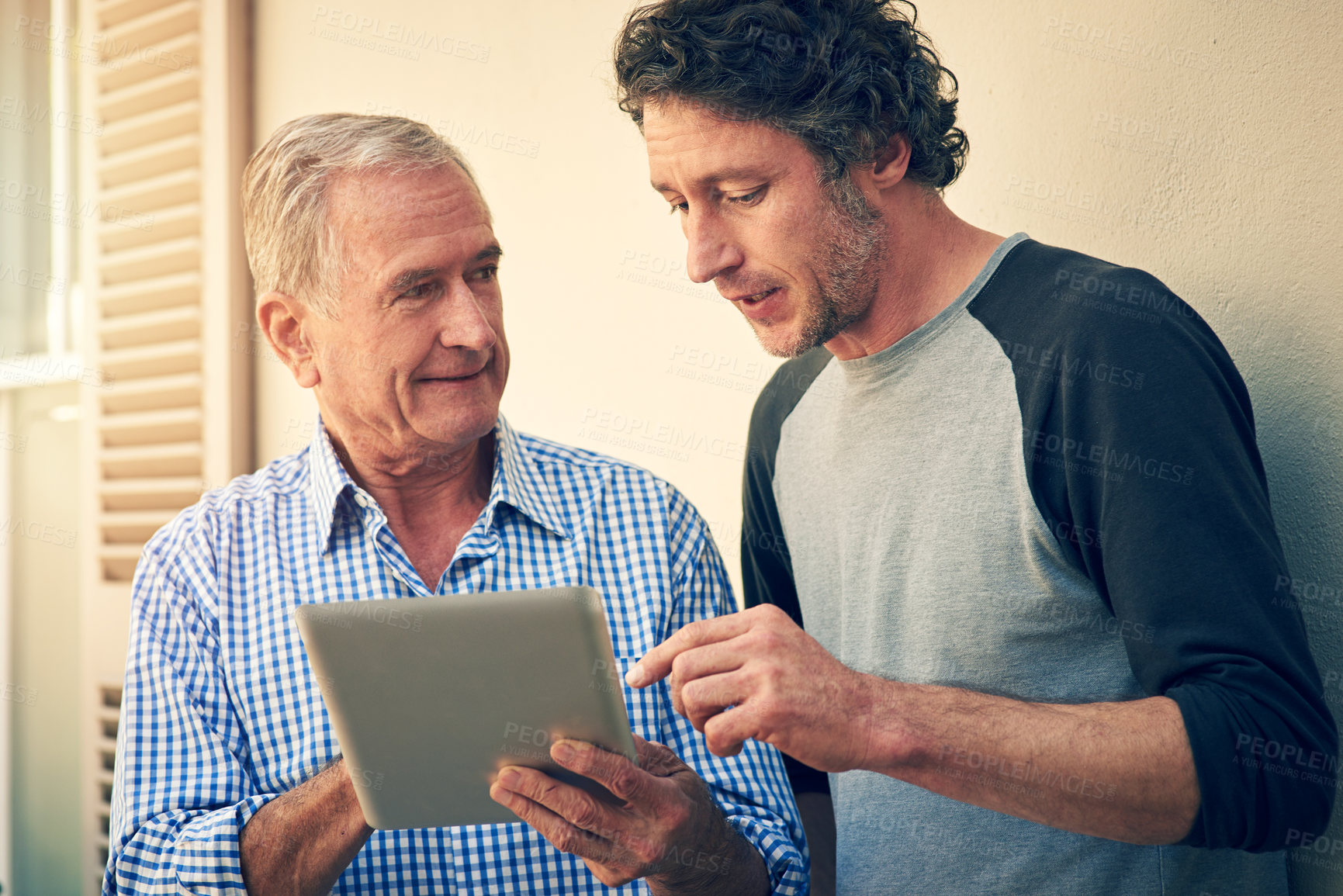 Buy stock photo Cropped shot of a man showing his elderly father how to use a tablet at home