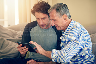 Buy stock photo Cropped shot of a man showing his elderly father how to use a tablet at home
