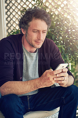 Buy stock photo Cropped shot of a man using his smartphone outside his home