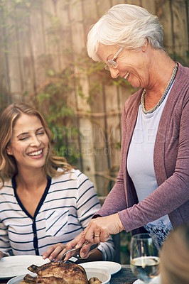 Buy stock photo Shot of an elderly woman carving a chicken at an outdoor family lunch