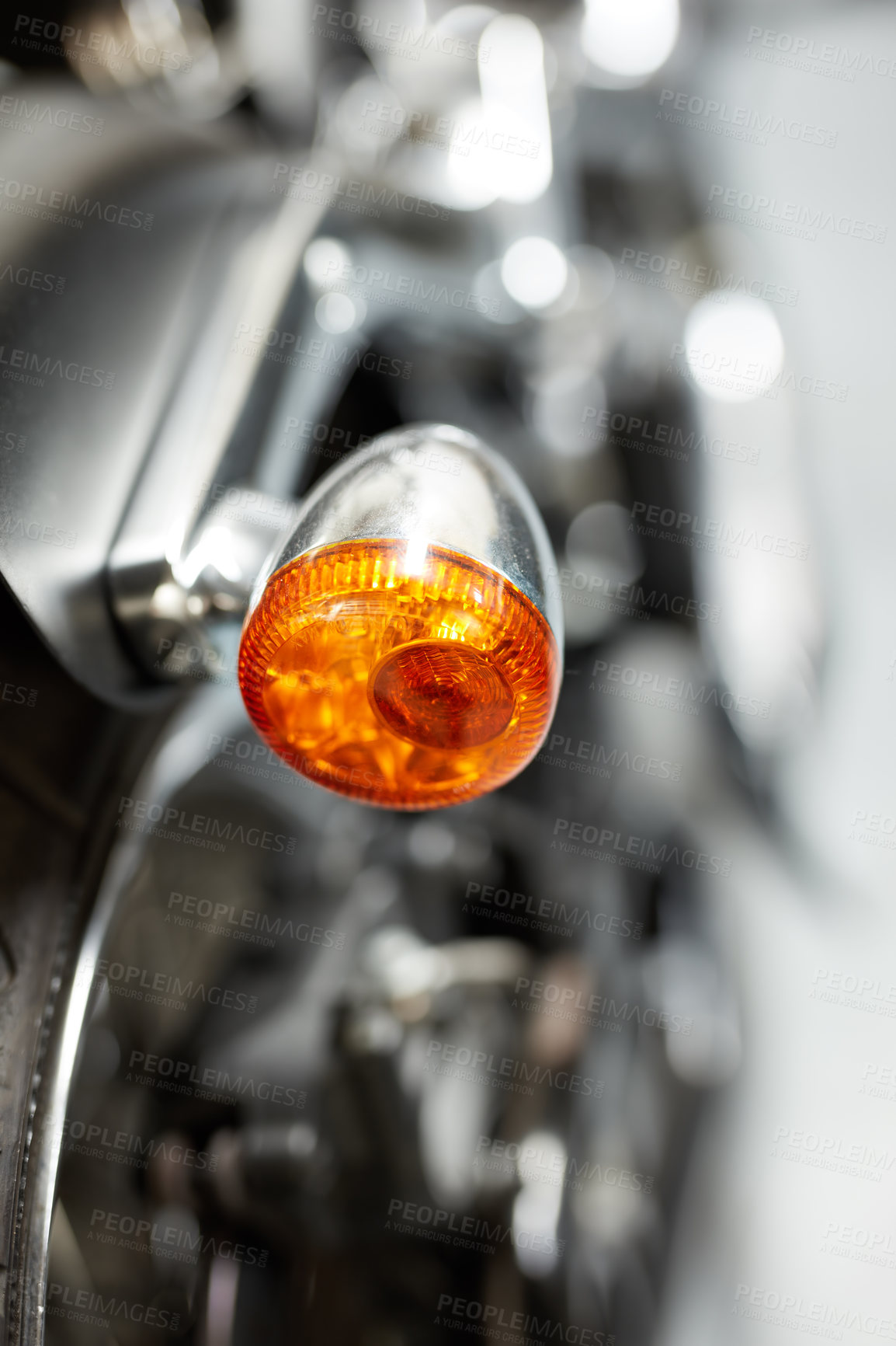 Buy stock photo The side indicator light of a motorbike. Closeup of signal gleam with the rear turning indicator light of a parked motorcycle. Popup of a rear signal glare with a chrome finish and orange LED light