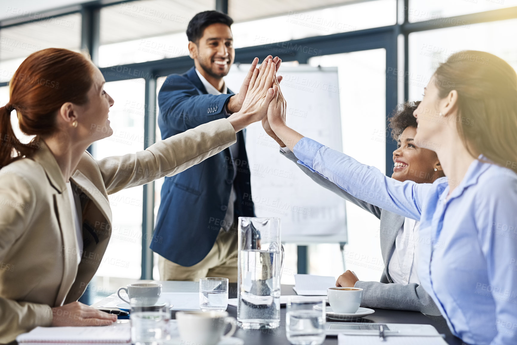 Buy stock photo Shot of a group of businesspeople high-fiving in the boardroom