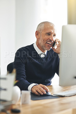 Buy stock photo Cropped shot of a mature businessman talking on his cellphone while using a computer