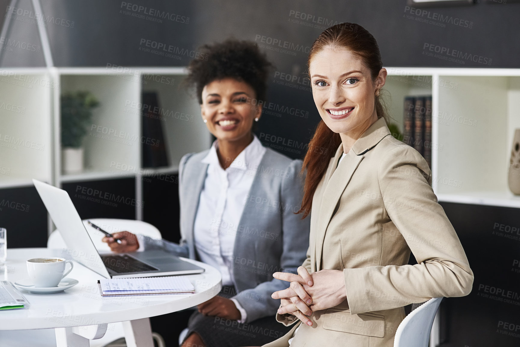 Buy stock photo Cropped shot of two businesswomen seated at a table with a laptop