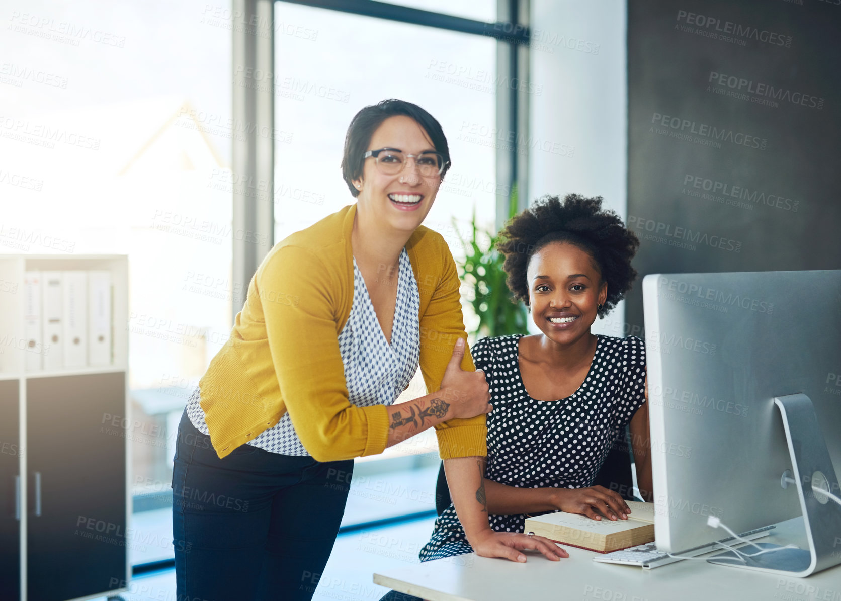 Buy stock photo Portrait of two young businesswomen working together in a modern office