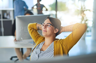 Buy stock photo Cropped shot of a young businesswoman relaxing at her desk in a modern office