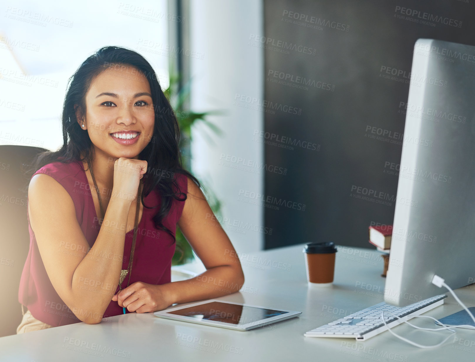 Buy stock photo Portrait of a confident young businesswoman sitting at a desk in a modern office