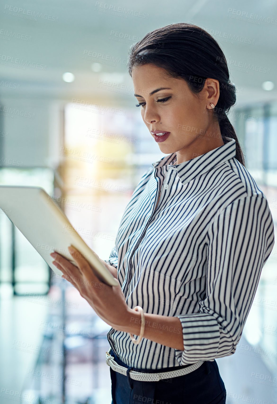 Buy stock photo Cropped shot of a young businesswoman working on a digital tablet in an office