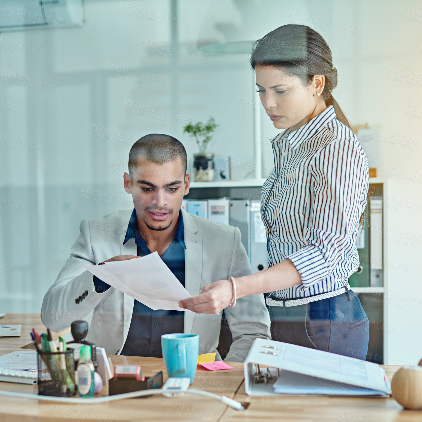 Buy stock photo Cropped shot of two businesspeople looking through some paperwork in an office
