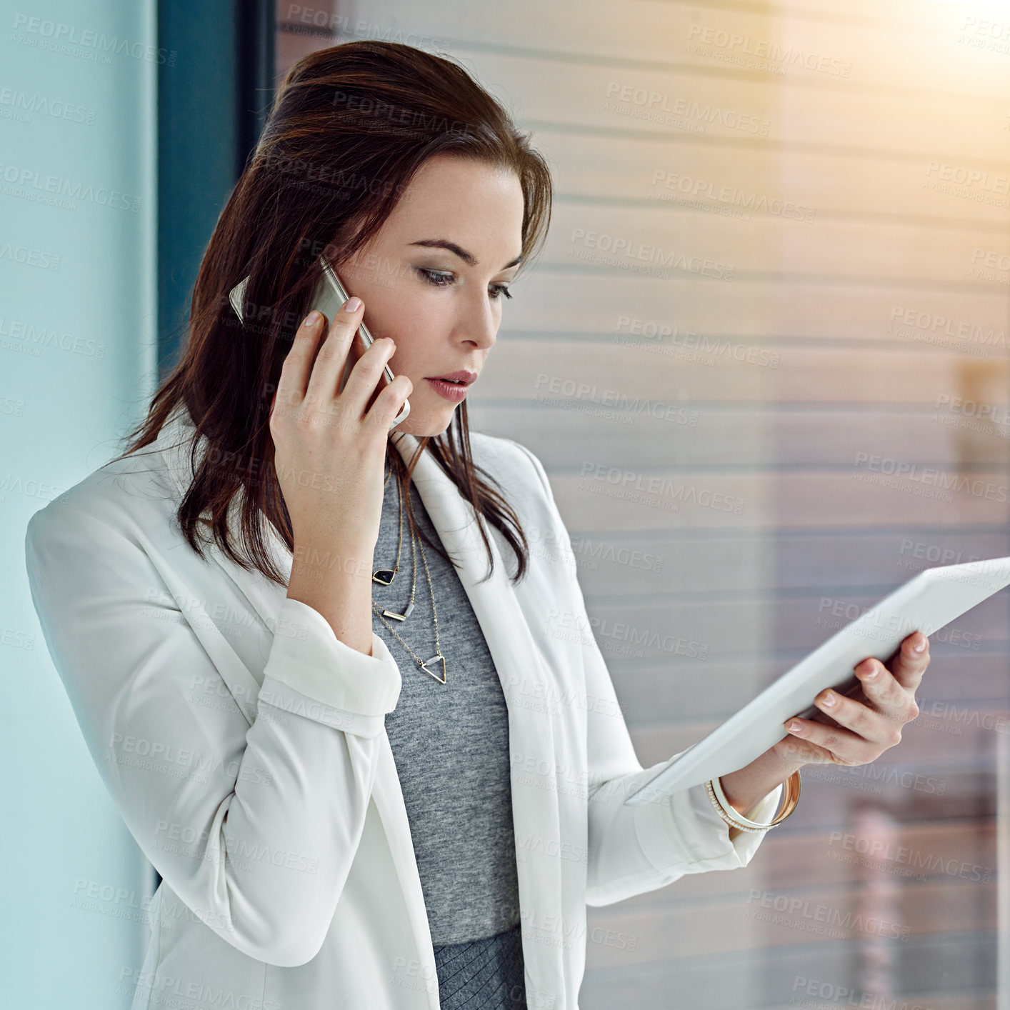 Buy stock photo Shot of a young businesswoman using a digital tablet and phone at work