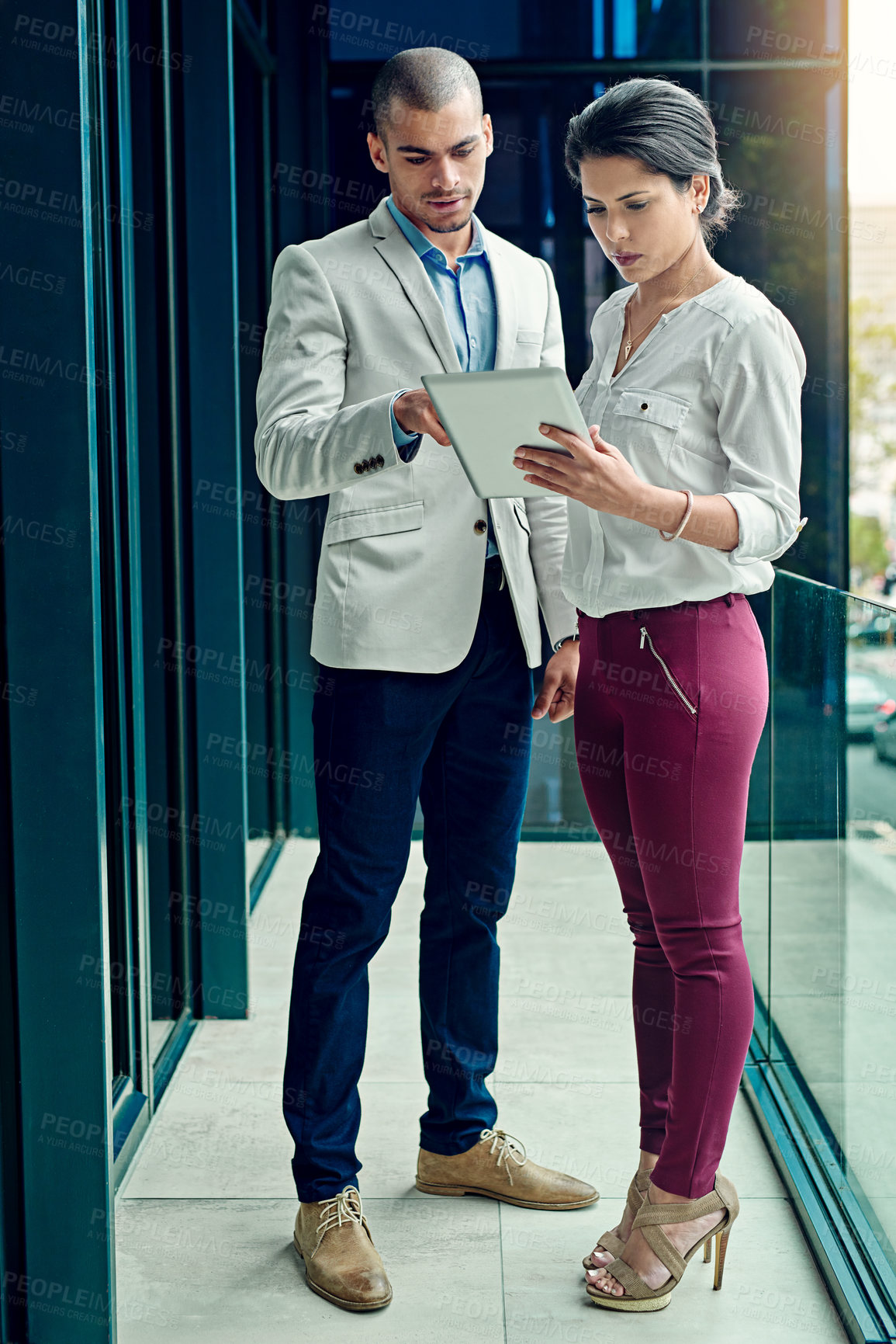 Buy stock photo Shot of two young coworkers using a digital tablet together at work