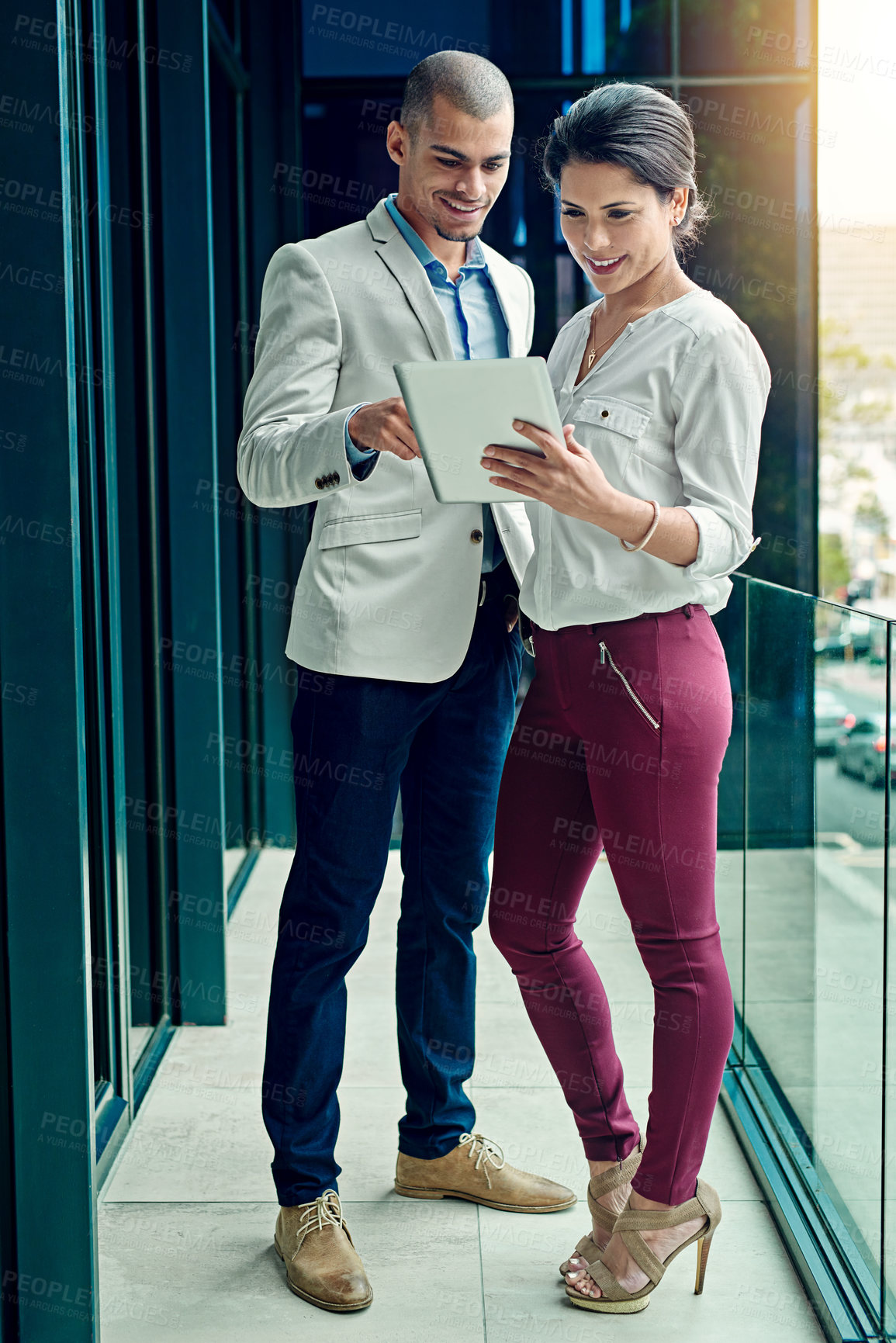 Buy stock photo Shot of two young coworkers using a digital tablet together at work