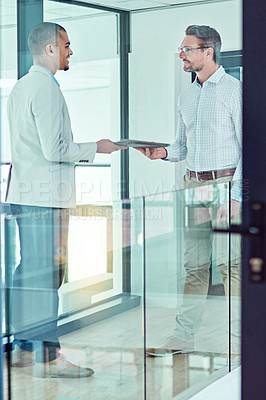 Buy stock photo Shot of a businessman handing a document to a colleague