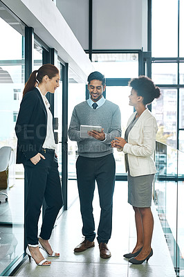 Buy stock photo Shot of a diverse group of young colleagues using a digital tablet together at work