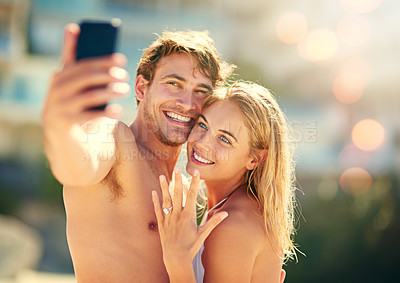 Buy stock photo Cropped shot of a young woman showing off her wedding ring while taking a selfie with her husband