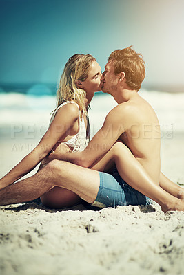Buy stock photo Cropped shot of a young couple kissing on the beach