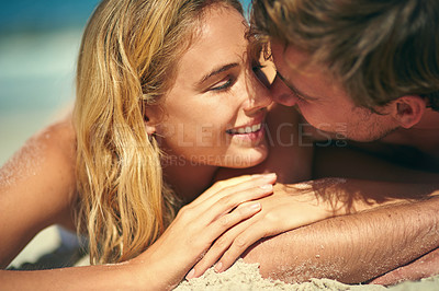 Buy stock photo Cropped shot of an affectionate young couple lying on the beach
