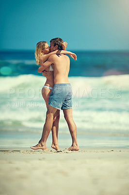 Buy stock photo Full length shot of an affectionate young couple kissing on the beach