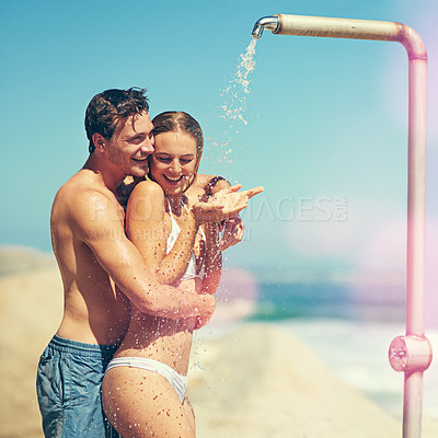Buy stock photo Cropped shot of an affectionate young couple showering on the beach