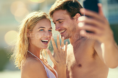 Buy stock photo Cropped shot of a young woman showing off her ring while taking a selfie with her boyfriend