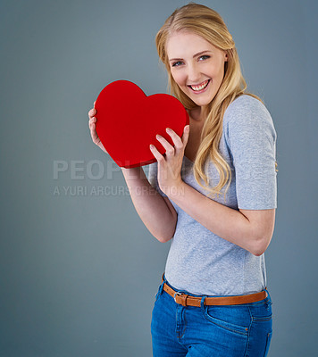 Buy stock photo Cropped studio shot of a young woman holding a red heart-shaped box