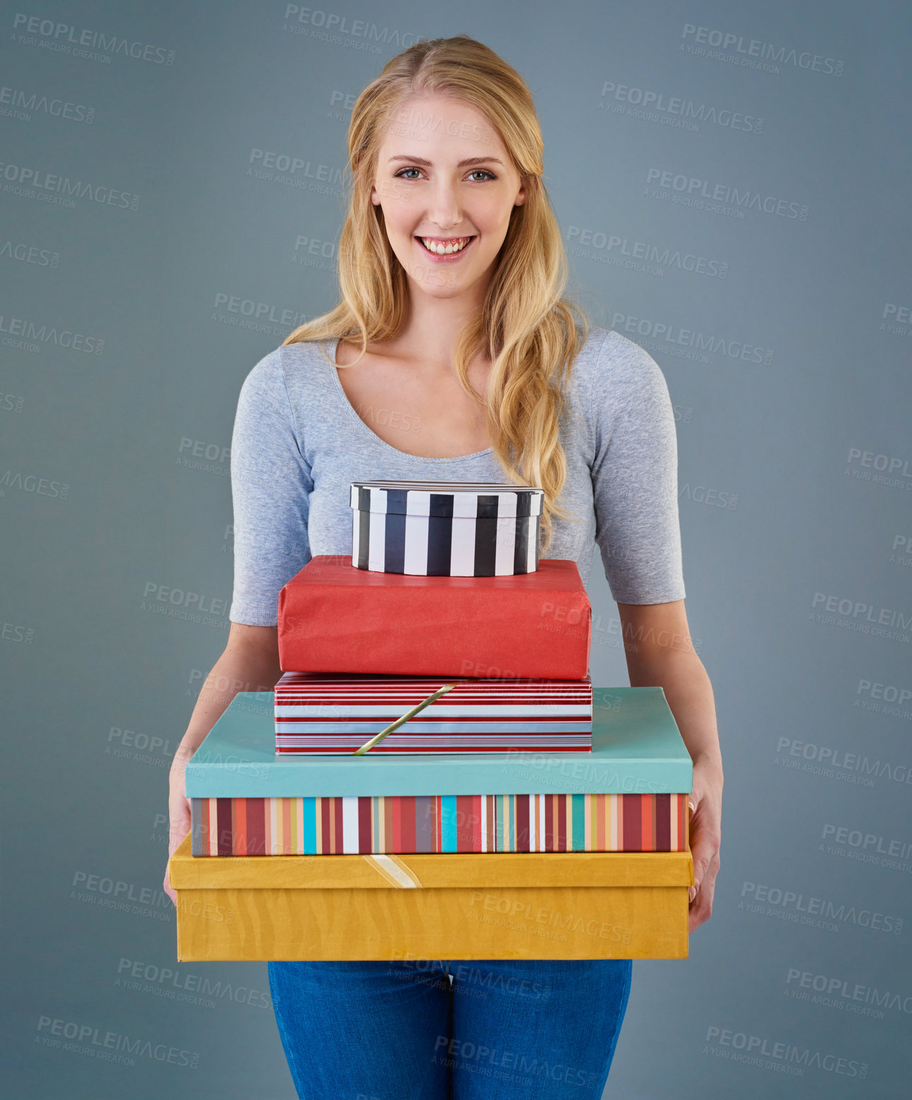 Buy stock photo Cropped studio shot of a young woman holding a stack of presents