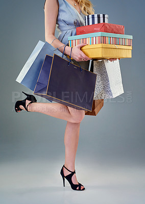 Buy stock photo Studio shot of a happy young woman holding a selection of shopping bags and gift boxes