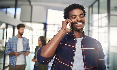 Buy stock photo Cropped shot of a young designer talking on a cellphone in an office with colleagues in the background