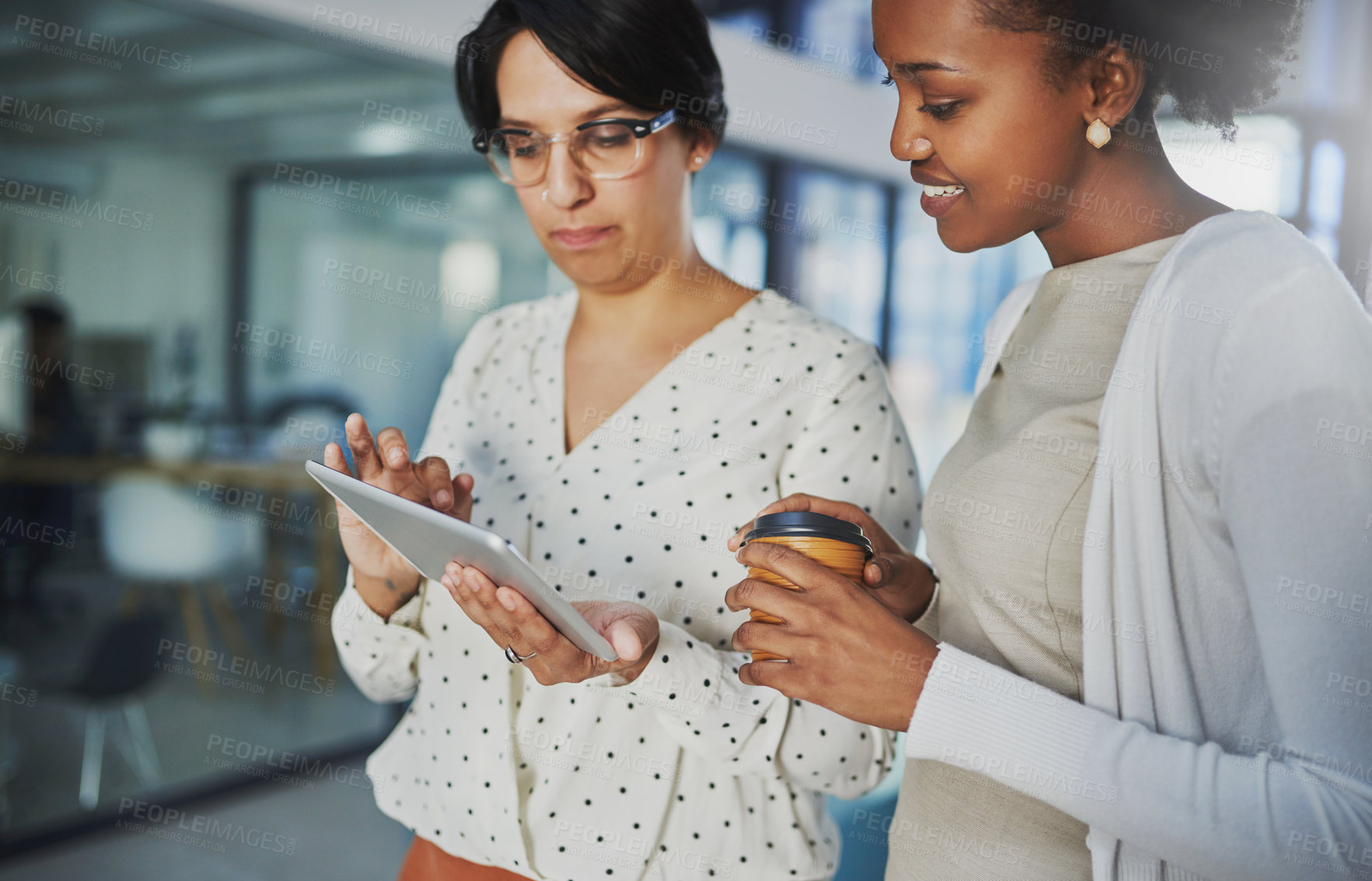 Buy stock photo Cropped shot of two businesswomen looking at a tablet in the office