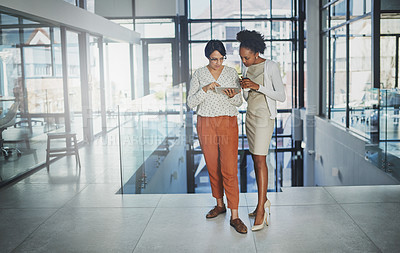 Buy stock photo Full length shot of two businesswomen looking at a tablet in the office