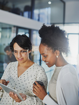 Buy stock photo Cropped shot of two businesswomen looking at a tablet in the office