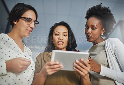 Buy stock photo Low angle shot of three businesswomen looking at a tablet in the office