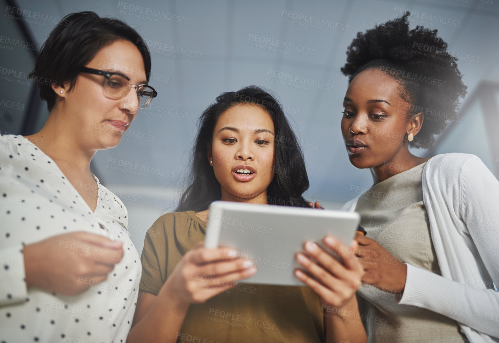 Buy stock photo Low angle shot of three businesswomen looking at a tablet in the office