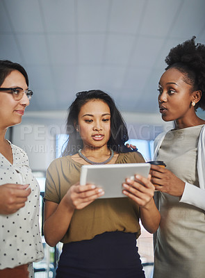Buy stock photo Cropped shot of three businesswomen looking at a tablet in the office