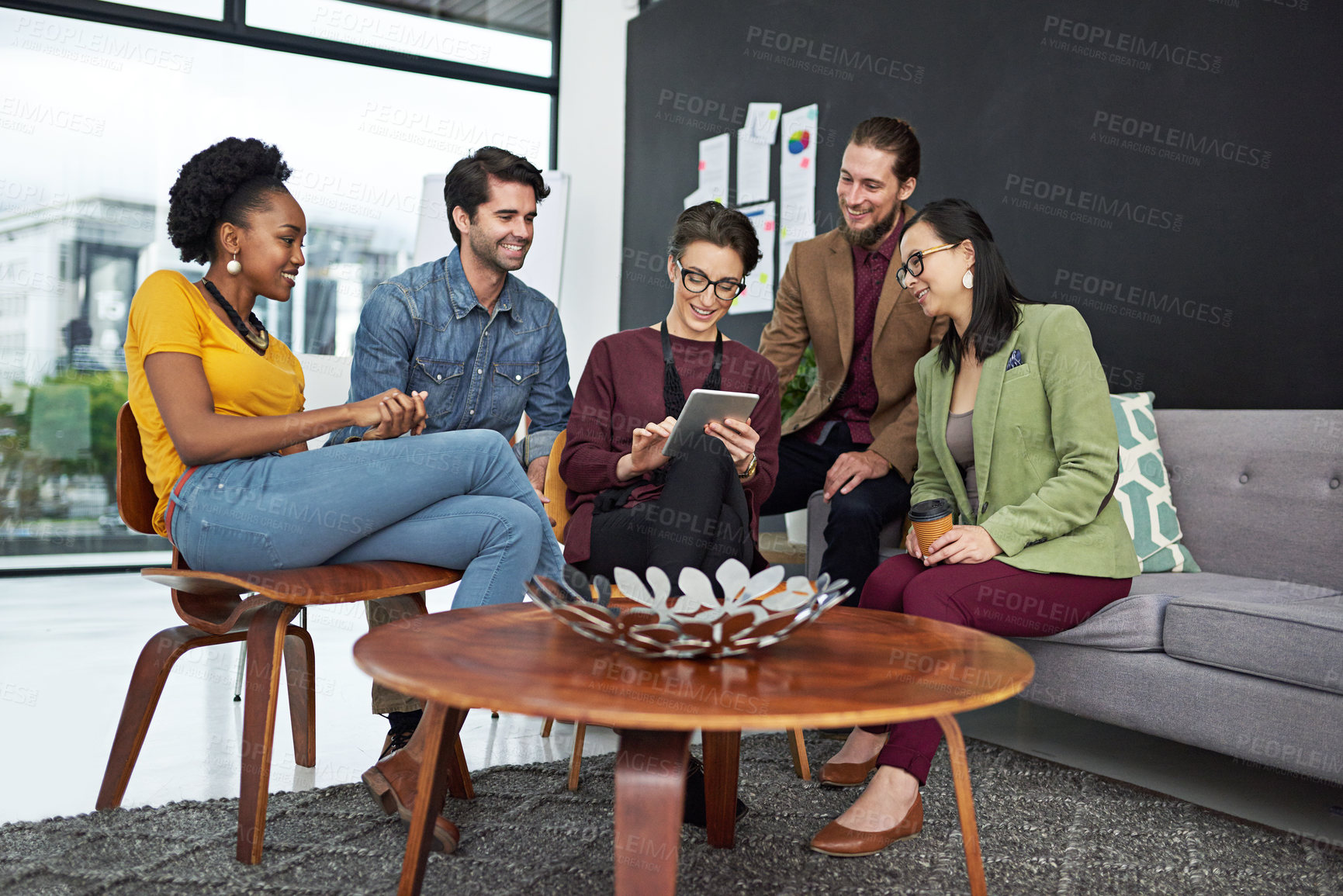 Buy stock photo Shot of a group of creative businesspeople looking at something on a tablet