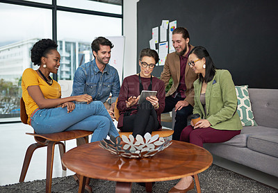Buy stock photo Shot of a group of creative businesspeople looking at something on a tablet