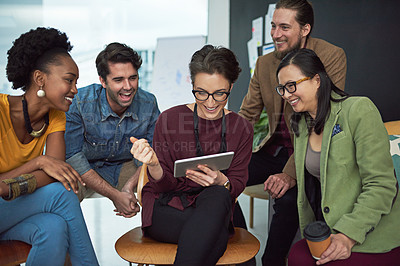 Buy stock photo Shot of a group of creative businesspeople looking at something on a tablet