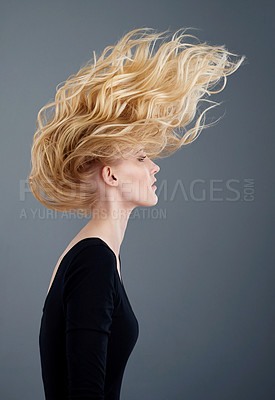 Buy stock photo Studio shot of an attractive young woman tossing her beautiful long blonde hair against a gray background