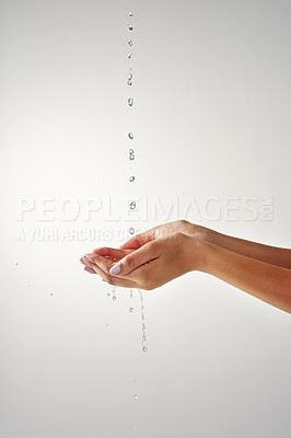 Buy stock photo Cropped shot of hands held out under a stream of water against a grey background
