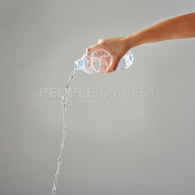 Buy stock photo Cropped shot of water being poured out of a bottle against a grey background