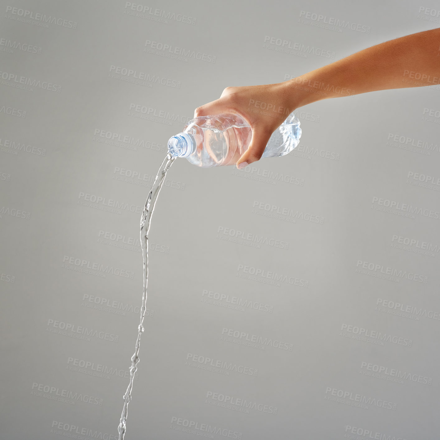 Buy stock photo Cropped shot of water being poured out of a bottle against a grey background