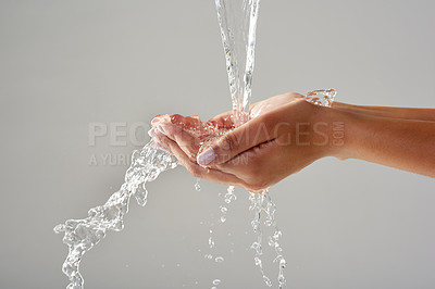 Buy stock photo Cropped shot of hands held out under a stream of water against a grey background
