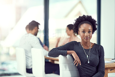 Buy stock photo Cropped portrait of a young woman sitting in the office with her colleagues in the background