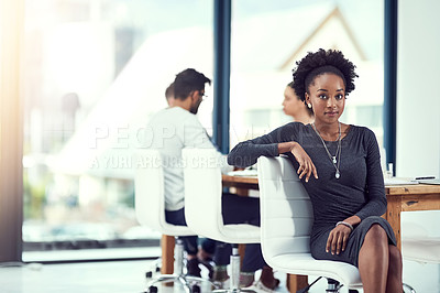 Buy stock photo Cropped portrait of a young woman sitting in the office with her colleagues in the background