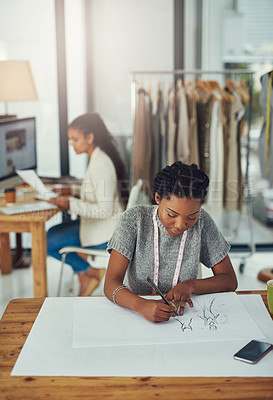 Buy stock photo Shot of a fashion designer working on her latest creation with her colleague blurred out