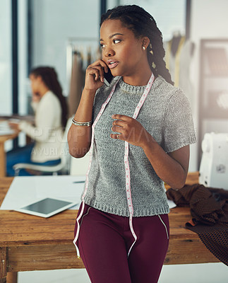 Buy stock photo Shot of a designer talking on her phone with her colleague blurred out in the background